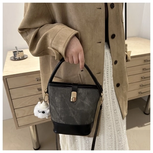 Detail of retro bucket bag with gold clasp, matte grey texture and plush sheep charm