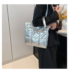 Detail of glossy silver quilted tote bag with metallic finish and padded texture