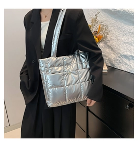 Quilted silver tote bag in metallic finish worn by model over a black blazer