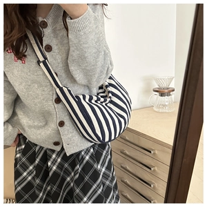 Close-up of blue and white striped canvas half-moon bag with adjustable shoulder strap
