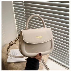 Détail d'un sac selle crème avec ferrures dorées et imprimé lettre de mode moderne