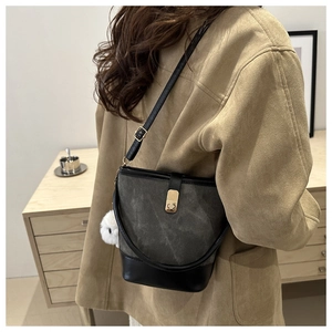 Detail view of contrast color bucket bag with leather trim and white plush charm accessory
