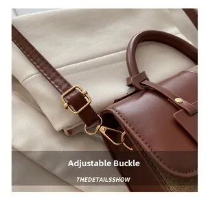 Close-up of polished gold adjustable buckle and leather strap on a brown handbag
