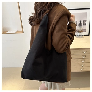 Detail of a black minimalist canvas tote bag showing its large capacity on a model's shoulder