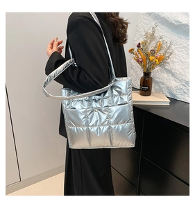 Close-up of silver quilted tote bag showing metallic texture and buckle pocket detail