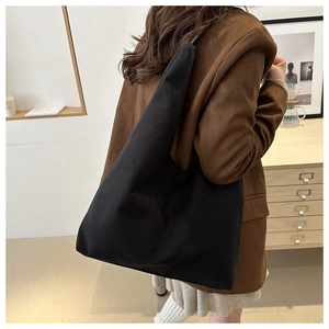 Detail of minimalist matte black tote bag with wide strap on shoulder, large capacity