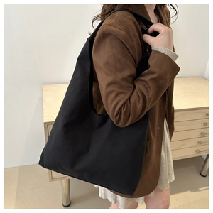 Detail of a large black vintage matte tote bag worn on shoulder for daily commute style