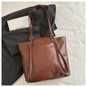 Dettaglio borsa tote in pelle marrone con spalline regolabili su uno sfondo blazer elegante