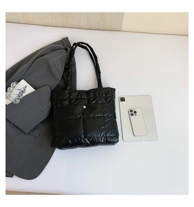 Flat lay of black quilted tote bag with office items for urban commuting look