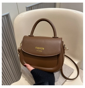 Detail of a brown leather saddle bag on a chair showing the top handle and strap
