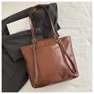 Dettagli delle fibbie argentate e della trama in pelle marrone di una borsa minimalista