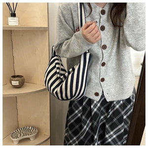 Detail of striped canvas hobo bag styled with a grey cardigan and checkered skirt