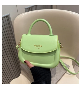 Detail of light green PU leather saddle bag with gold logo on a beige chair