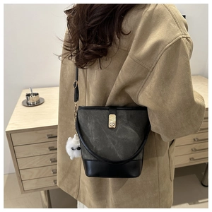 Model wearing a vintage dark grey canvas bucket bag with black leather trim and plush charm
