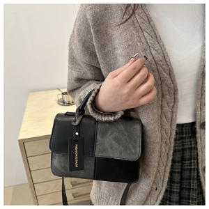 Detail view of a color-block square bag showing the smooth leather and matte suede textures