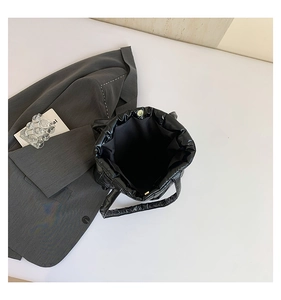 Detail of black puffer tote bag showing magnetic snap closure and spacious padded interior