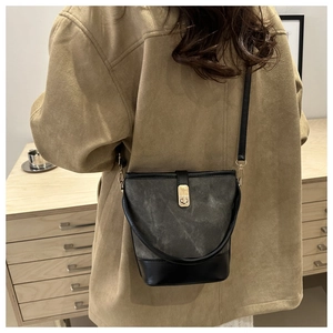 Detail of retro bucket bag with gold buckle and black leather trim on vintage cabinet