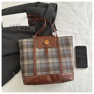 Dettaglio della borsa tote a righe con finiture in pelle marrone e fibbia retrò