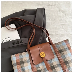 Vista dettagliata della borsa tote a quadri con manico in pelle marrone su sfondo elegante