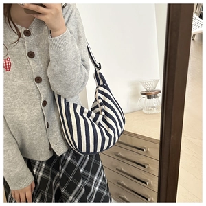 Detail of blue and white striped canvas hobo bag with adjustable black shoulder strap