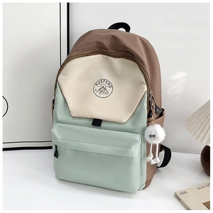 Close-up of tricolor waterproof nylon backpack with plush ball charm and logo detail