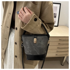 Detail of grey bucket bag with vintage canvas texture and golden turn-lock buckle