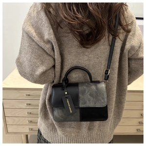 Detail of a chic patchwork crossbody bag featuring grey suede and black leather textures