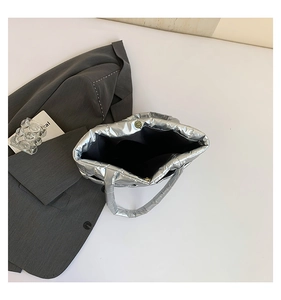 Detail view of quilted silver metallic tote bag featuring magnetic snap closure and soft lining