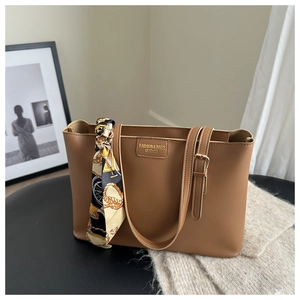 Brown leather tote bag featuring a decorative printed scarf and embossed logo on black seat
