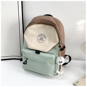 Detail of color-block nylon backpack featuring a mountain logo and plush pompom charm