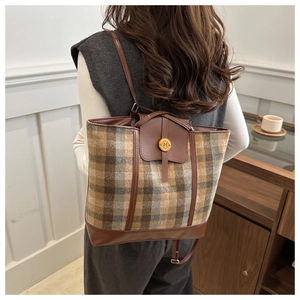 Dettaglio borsa shopper a scacchi con bordi in pelle e logo metallico portata a spalla