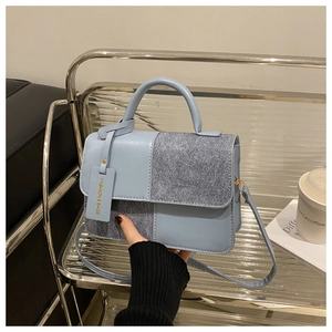 Dettaglio della borsa quadrata azzurra con cuciture in pelle su supporto metallico