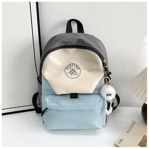 Close-up of color-block nylon backpack with XUEFENG logo and white plush ball pendant
