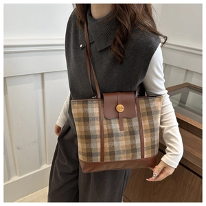 Dettaglio della borsa tote vintage a quadri con finiture in pelle marrone e chiusura dorata