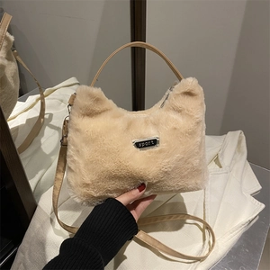 Gros plan sur le tissu peluche beige et le badge sport en métal du sac à bandoulière