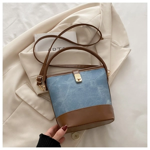 Detail of blue denim and brown leather bucket bag with gold metallic twist lock