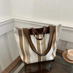 Detail of vintage canvas tote with brown leather handles and striped pattern