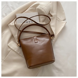 Top view of brown leather bucket bag with top handle and adjustable shoulder strap on blazer