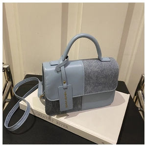 Detail of a color-block handbag with smooth light blue and dark gray textured fabric panels