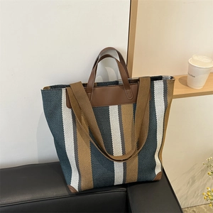 Macro detail of large striped canvas tote bag showing weave texture and leather handle