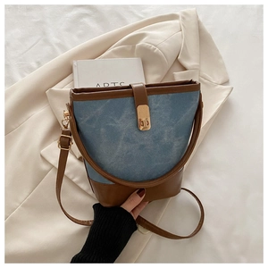 Detailed shot of a vintage denim and brown leather bucket bag with gold hardware