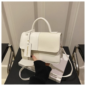 Detail of color-block flap handbag with top handle and delicate crossbody strap