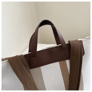 Close-up of woven tote bag texture with brown leather handles and striped fabric details