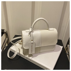 Detail of cream minimalist crossbody bag featuring contrast leather texture and fashion tag