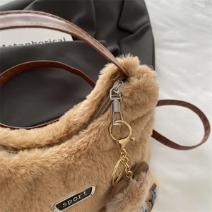 Détail d'un sac bandoulière en peluche kaki avec breloque ours doré et bandoulière