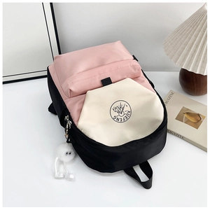 Detail of color-block nylon backpack with deer logo, plush ball charm and pink accents