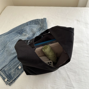 Large black canvas tote bag showing spacious interior with laptop and umbrella