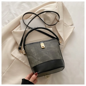 Detail of gray vintage bucket bag with black leather base and gold square metal twist lock
