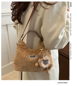 Détail du sac bandoulière en peluche marron avec plaque sport et charm de poupée douce