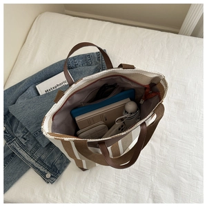Top view of spacious interior of striped canvas tote bag with laptop and daily essentials